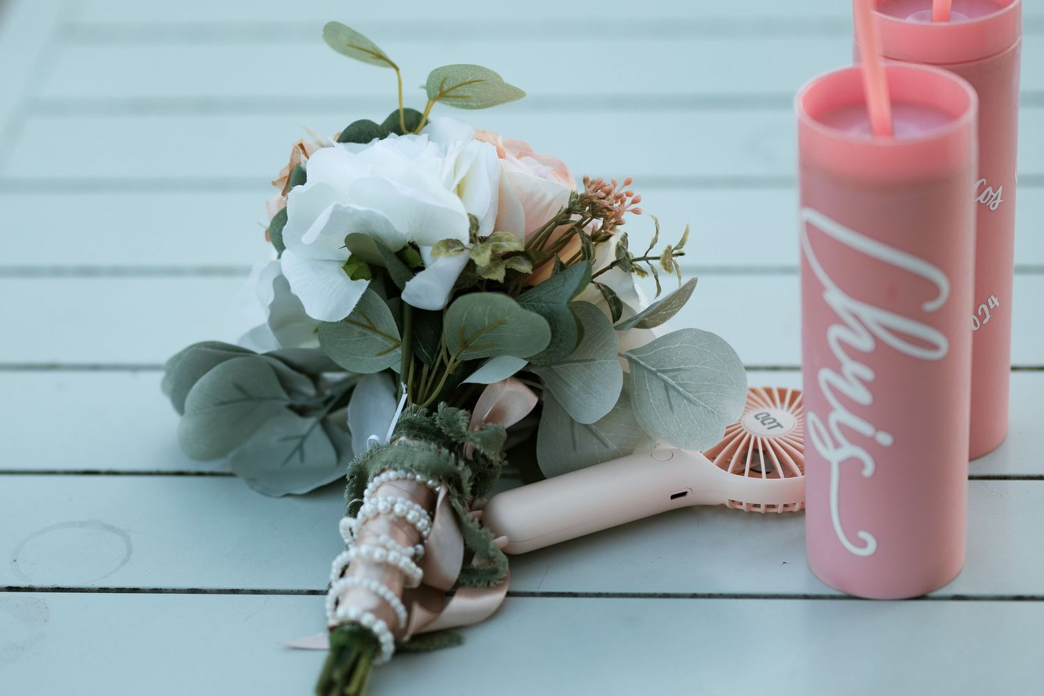 Pink candles and eucalyptus leaves create an elegant table setting at a wedding reception.