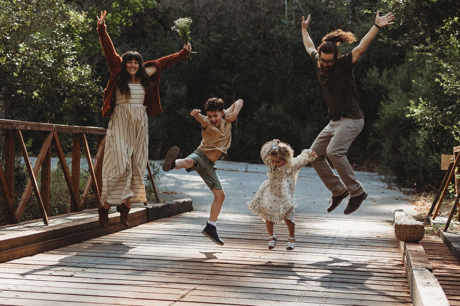Group of people dancing and jumping with joy on a sunlit outdoor patio.