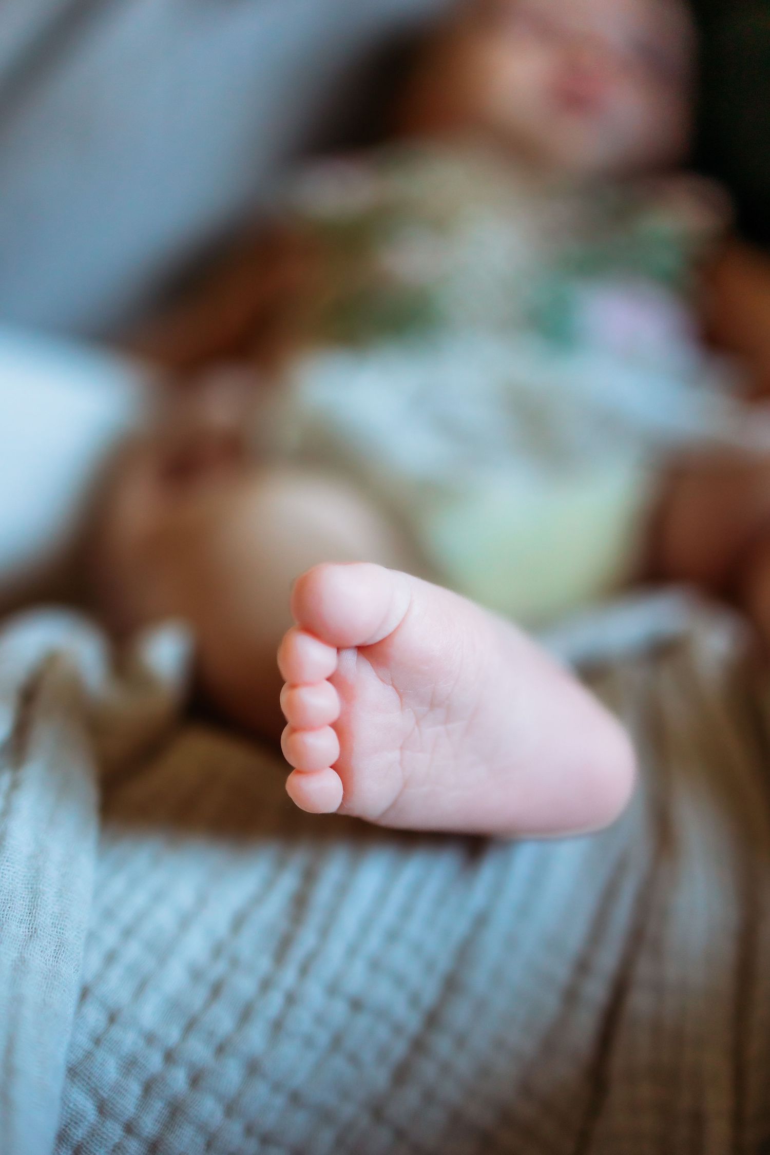 Close-up view of tiny baby feet against a soft textured background.