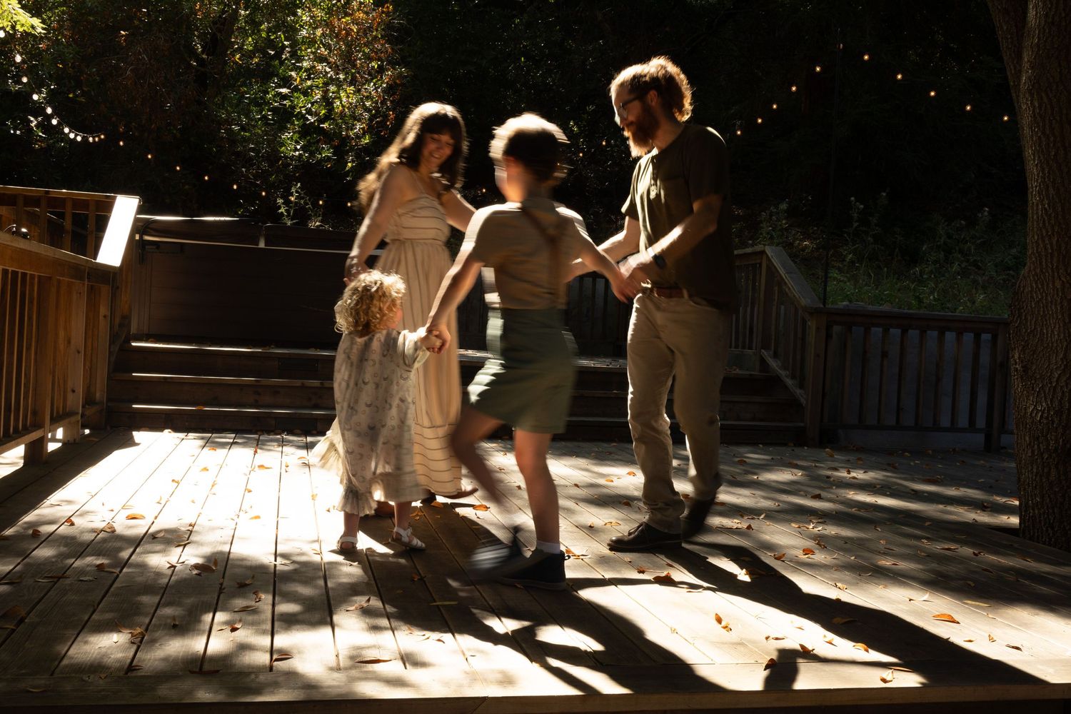 Dappled sunlight creates shadows on a wooden deck outdoors.