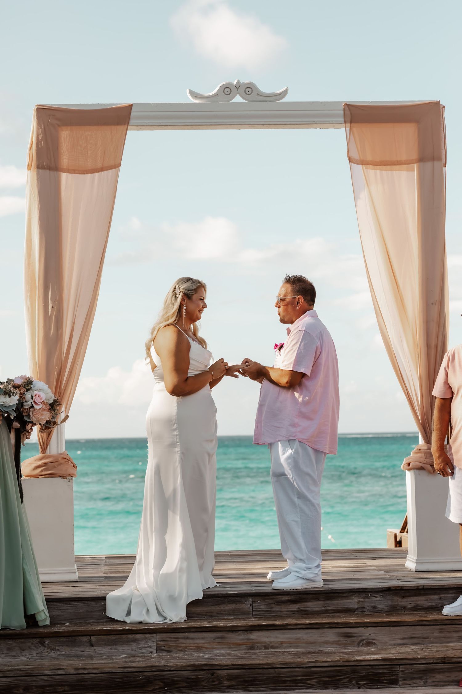Wedding ceremony sequence on a beachfront deck with flowing curtains and ocean backdrop.