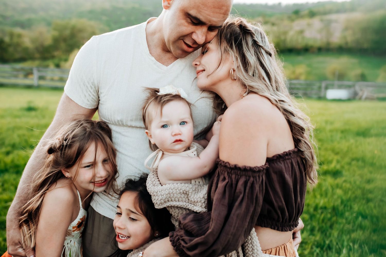 Family embracing in green field during golden hour photography session.