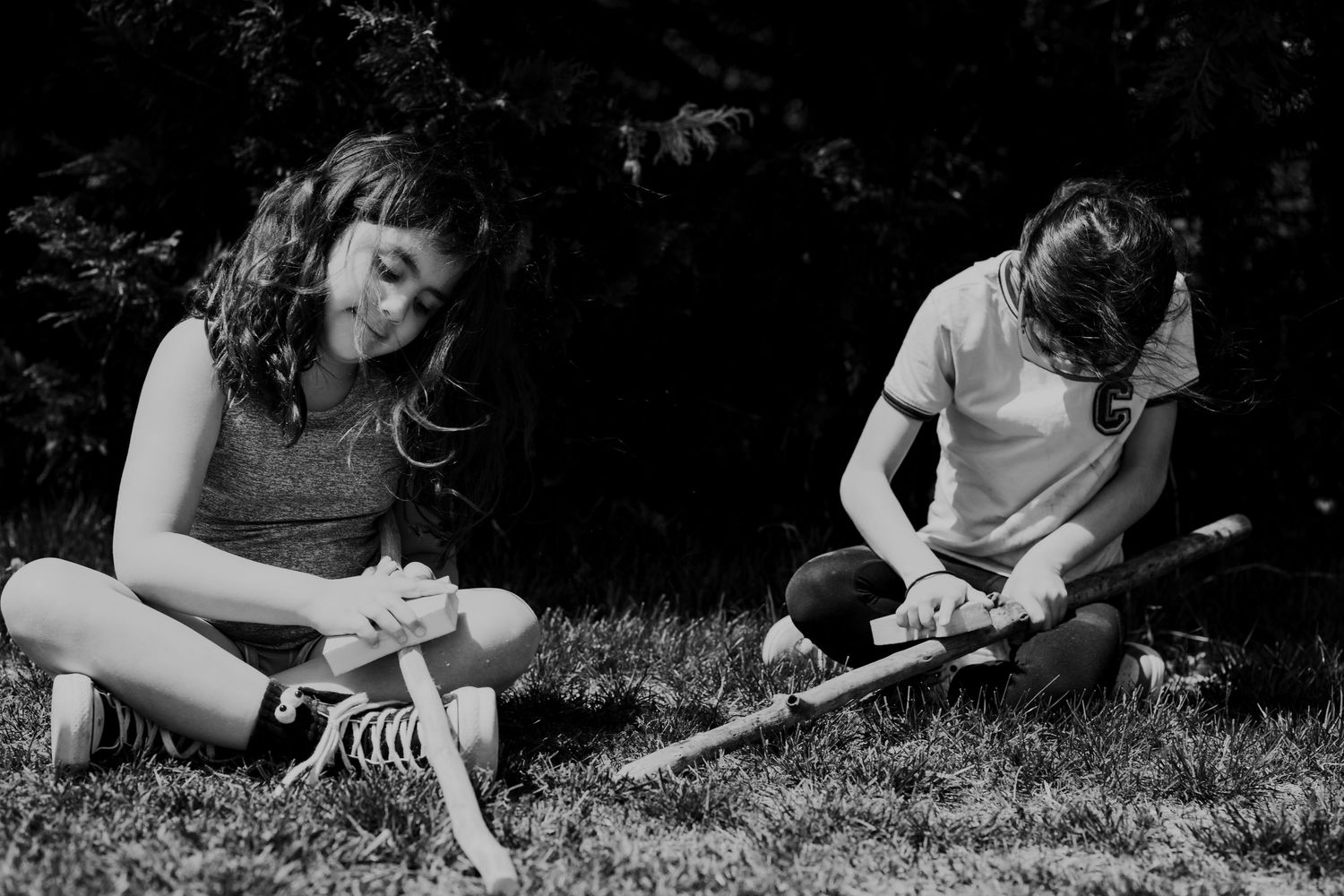Black and white image of people lying on grass outdoors.