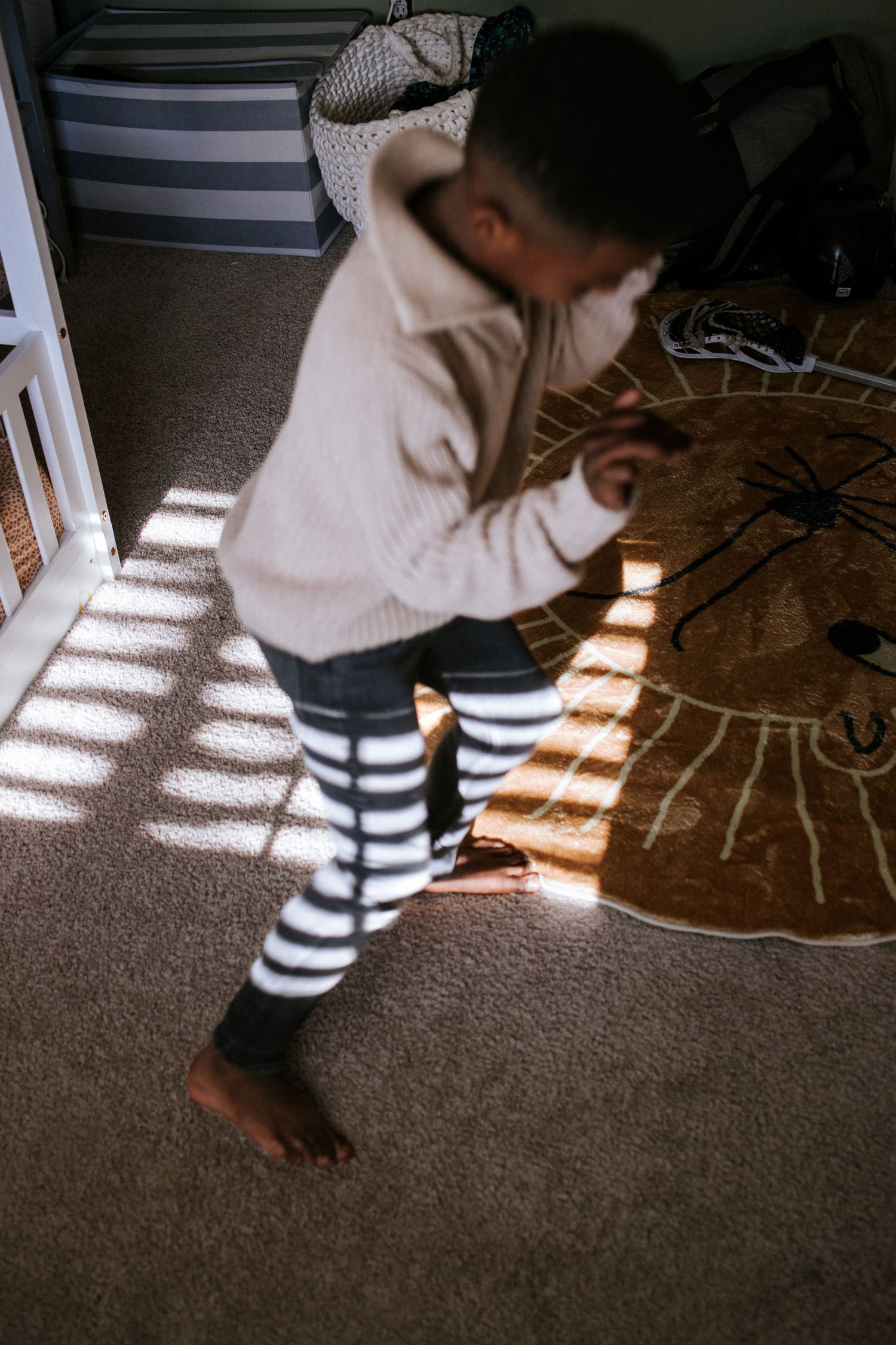 Sunlight casts dramatic shadows on a carpet through window blinds.