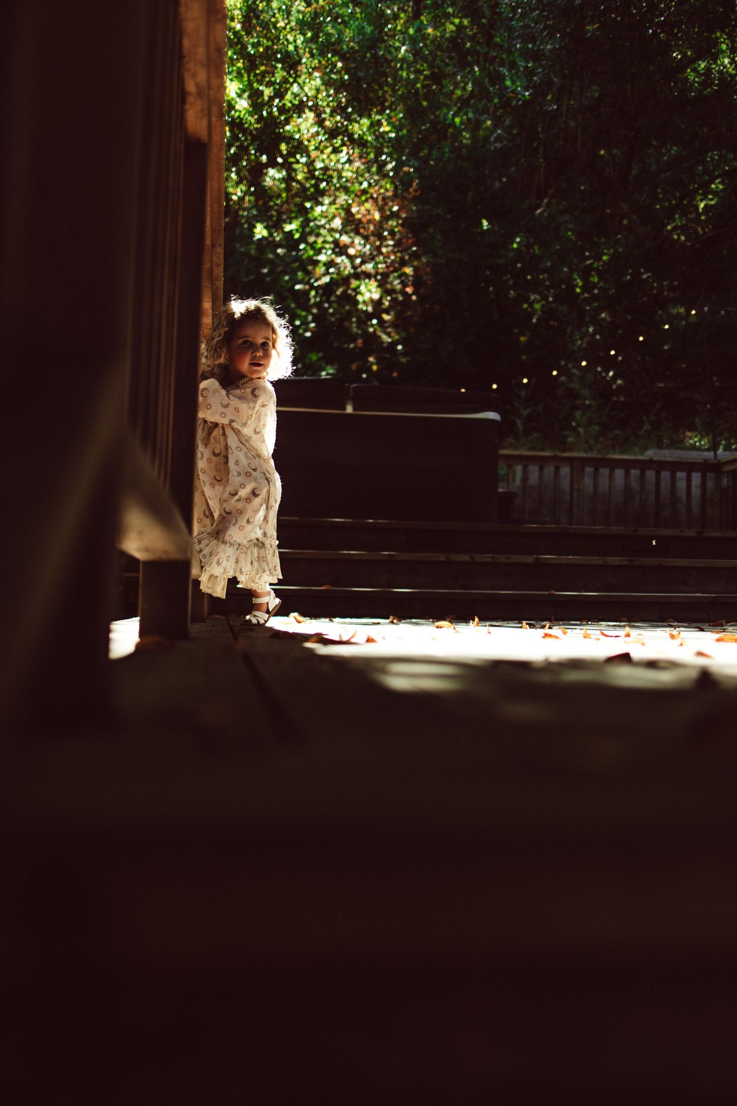 Shadows and light play across a wooden deck as figures move in the sunlight.