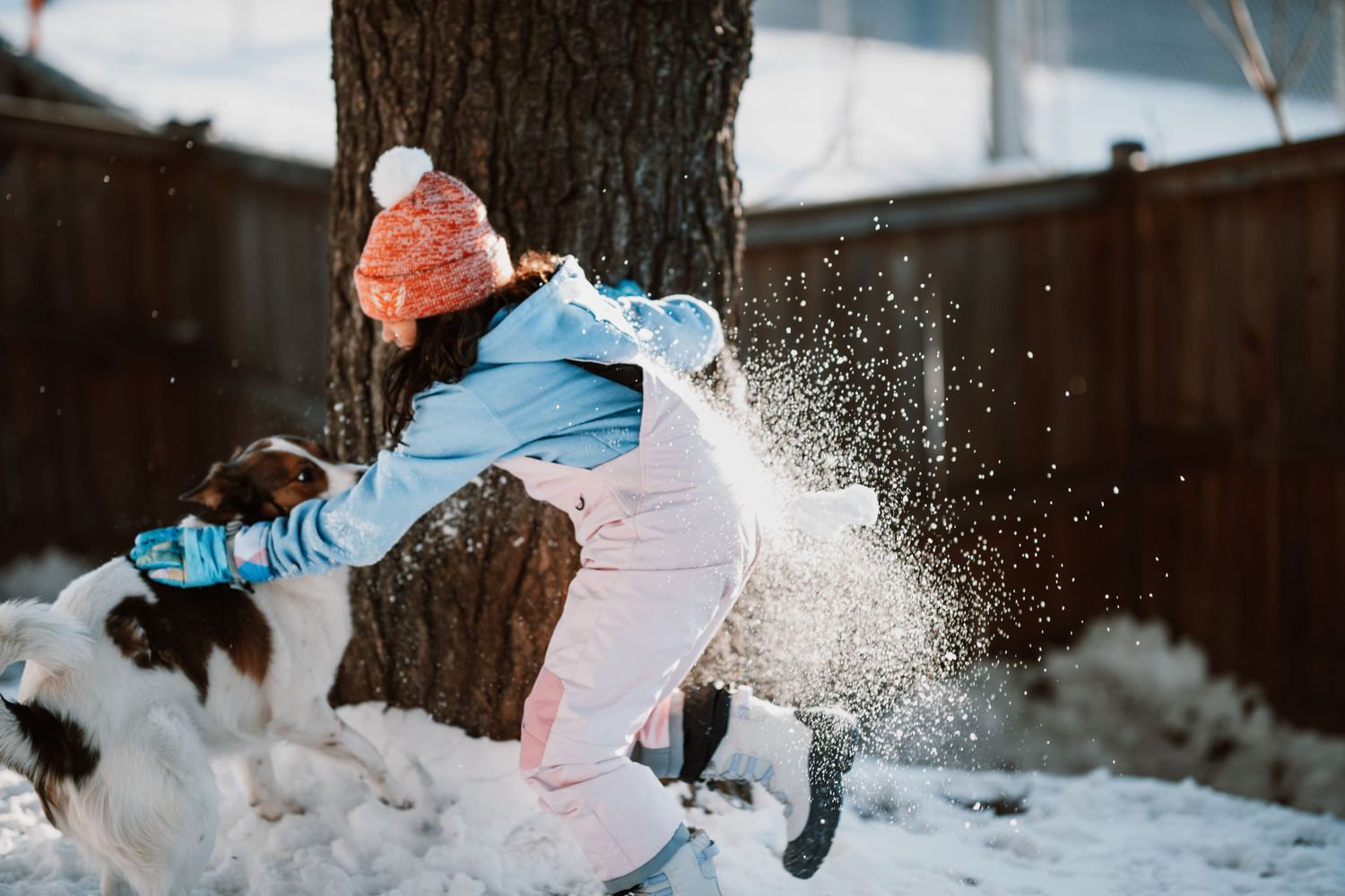 People playing and kicking up snow during winter activities outdoors.