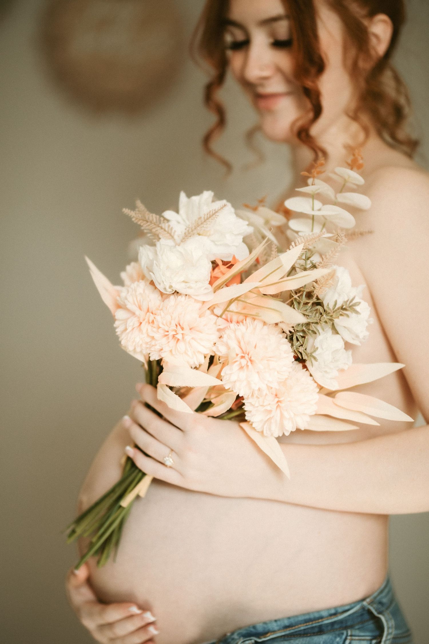 Delicate floral bouquet with pale pink blooms held against soft neutral background.