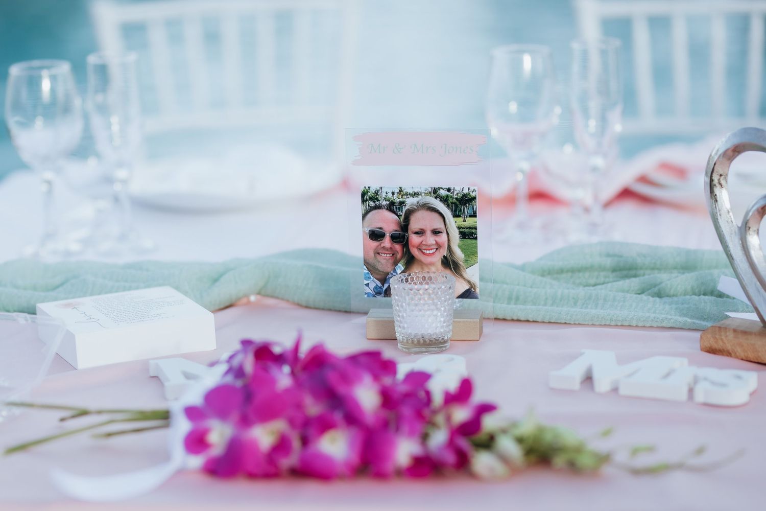 Pink floral arrangements and table settings at an elegant outdoor wedding reception.
