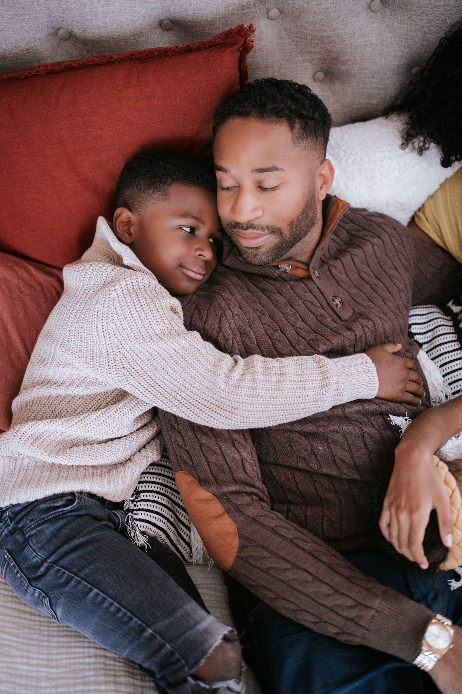 Cozy family scene with people relaxing together on red couch.
