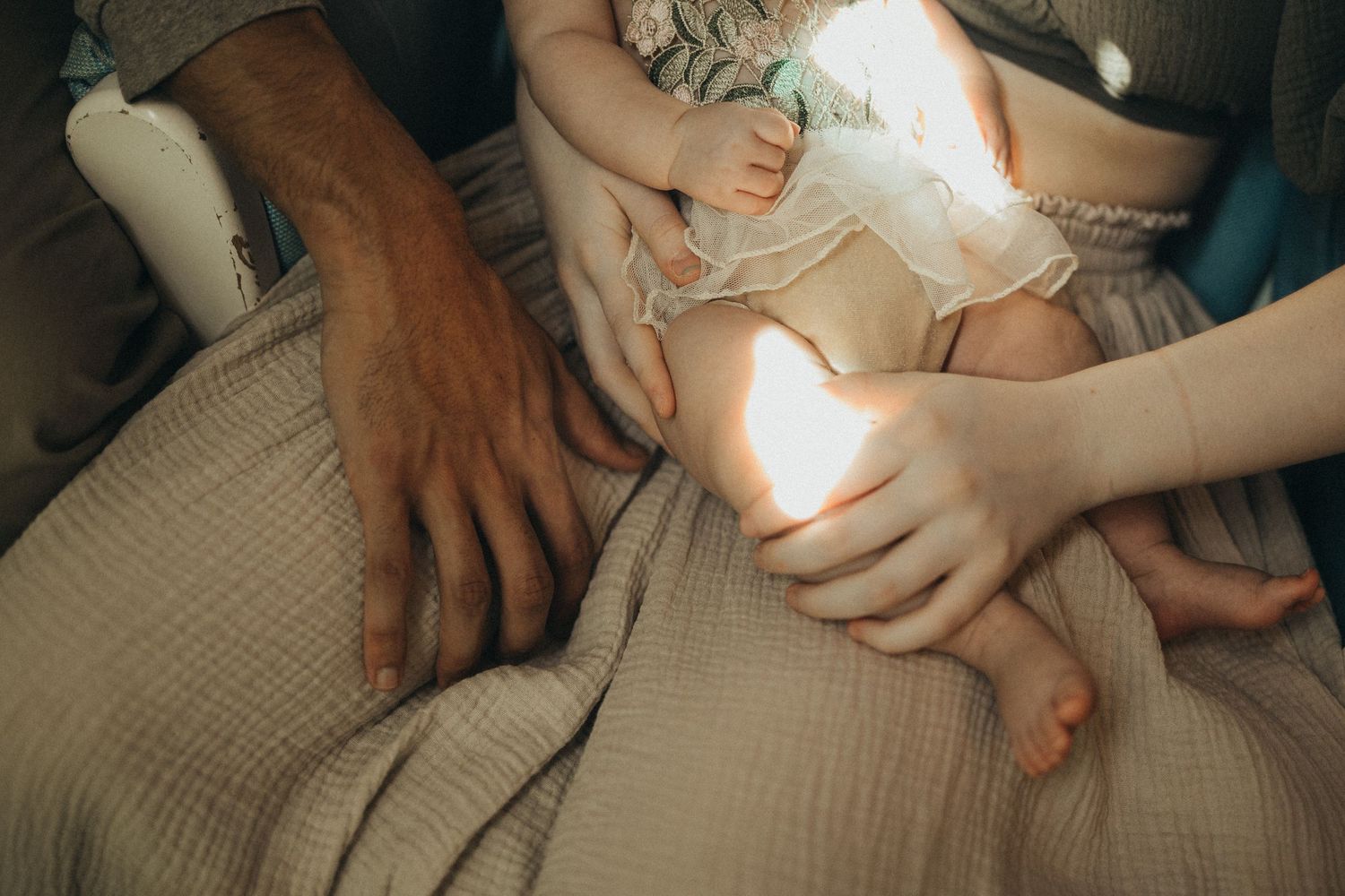 Hands tenderly touching against textured fabric in muted lighting.