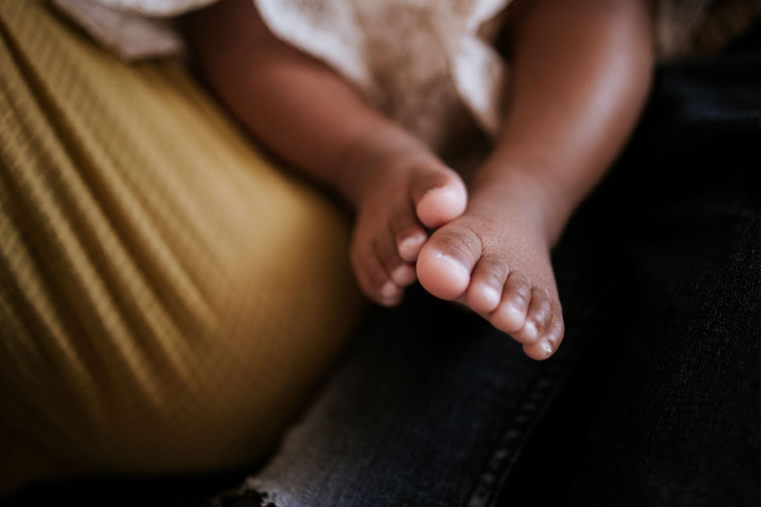 Close-up view of small feet against a soft yellow background.