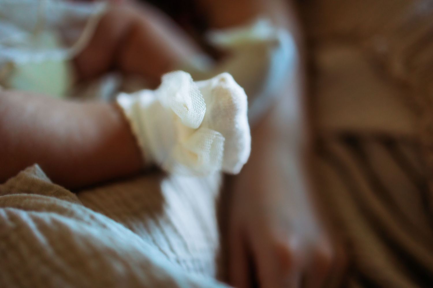 Gentle hands caressing delicate white fabric in soft natural light.