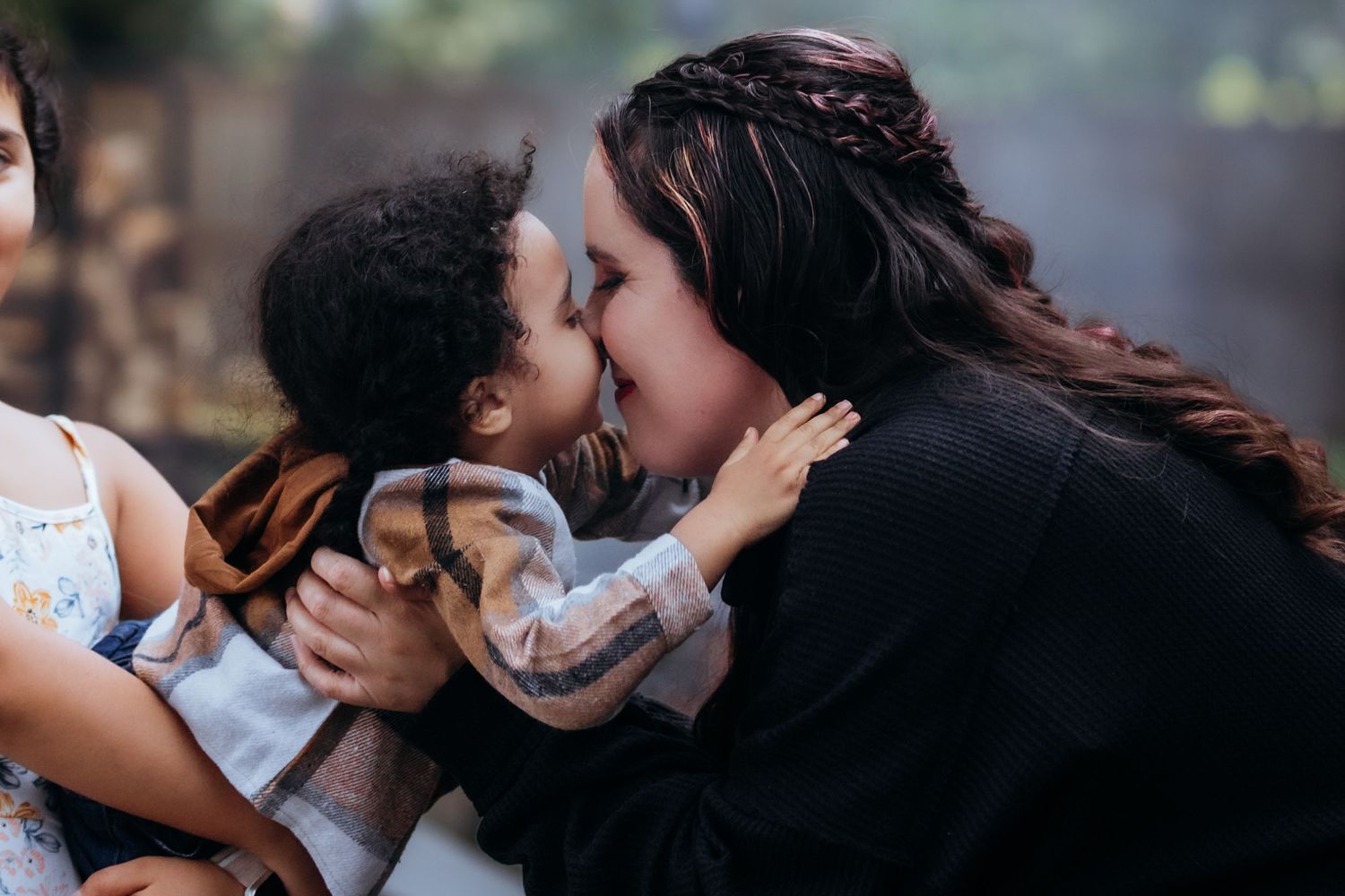 Candid moments of affection captured in natural lighting outdoors.