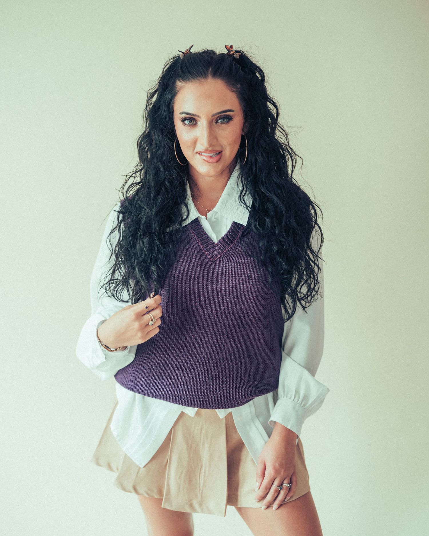Fashion model wearing purple sweater vest and white shirt poses in stylized portrait series.