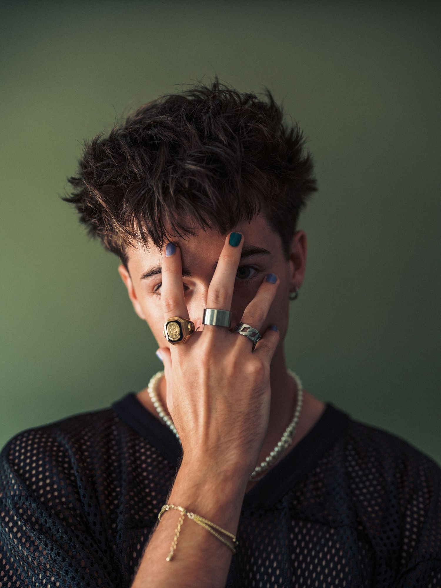 Dramatic portrait series showing person with hands covering face wearing mesh top.