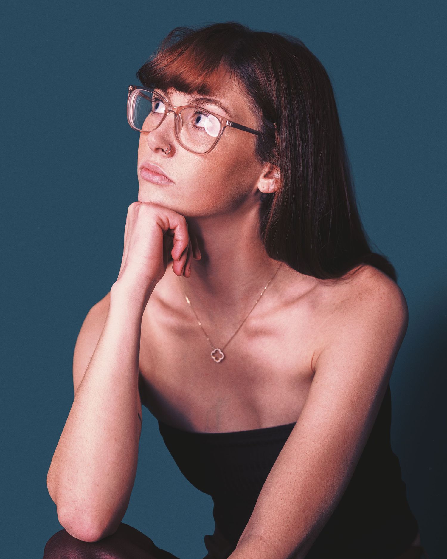 A figure in glasses and dark hair poses artistically against a blue backdrop in a series of dramatic angles.