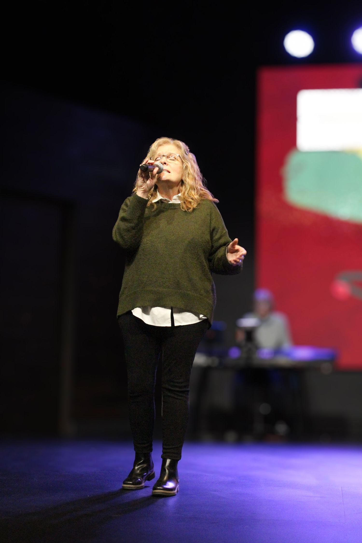 Woman singing on stage under stage lights
