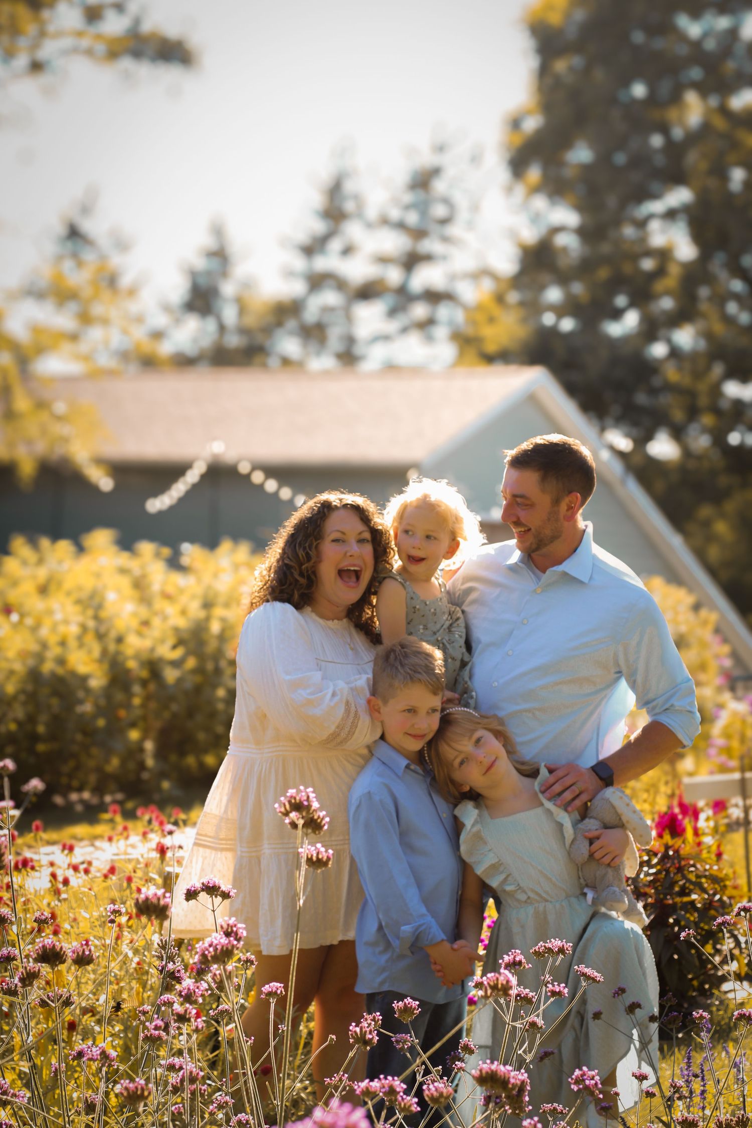 a family photo; family laughing and smiling while standing in a field of flowers
