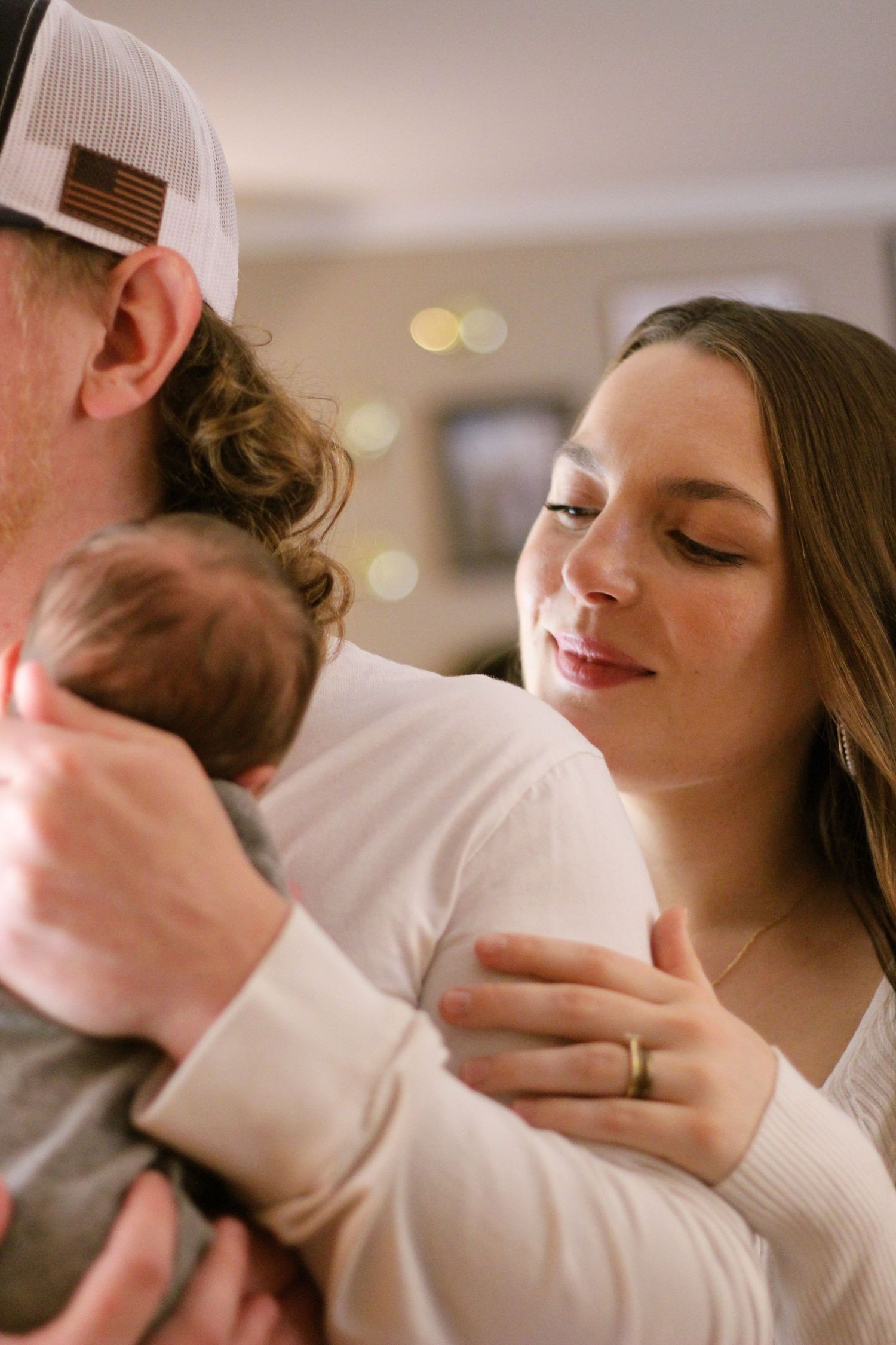a father holding newborn son with mother looking over the should of the father to look at her baby.