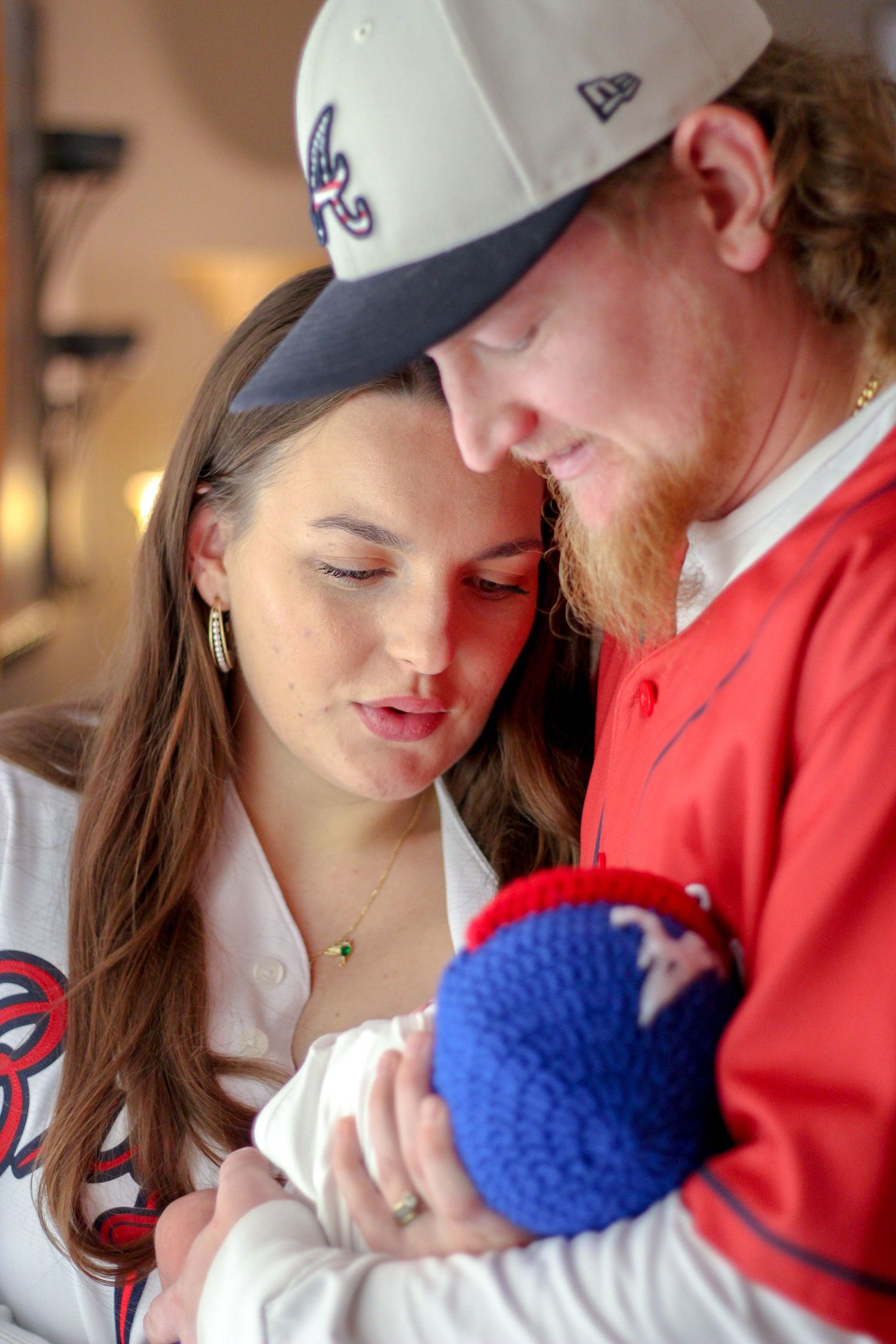 a mother and father holding their newborn baby. The family is dressed in Atlanta Braves Baseball gear because it's their favorite team.