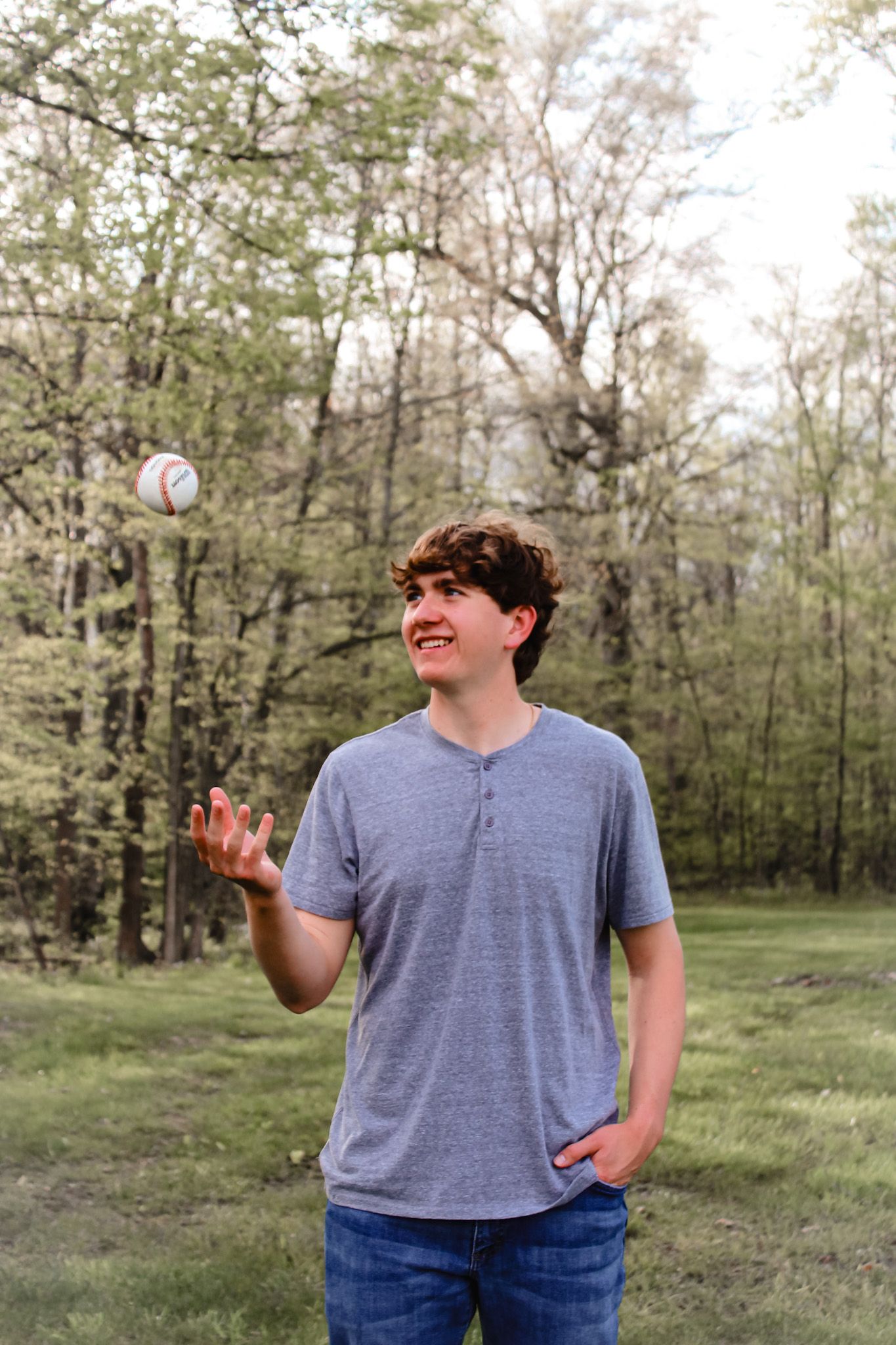 a male high school senior tossing a baseball up in the air