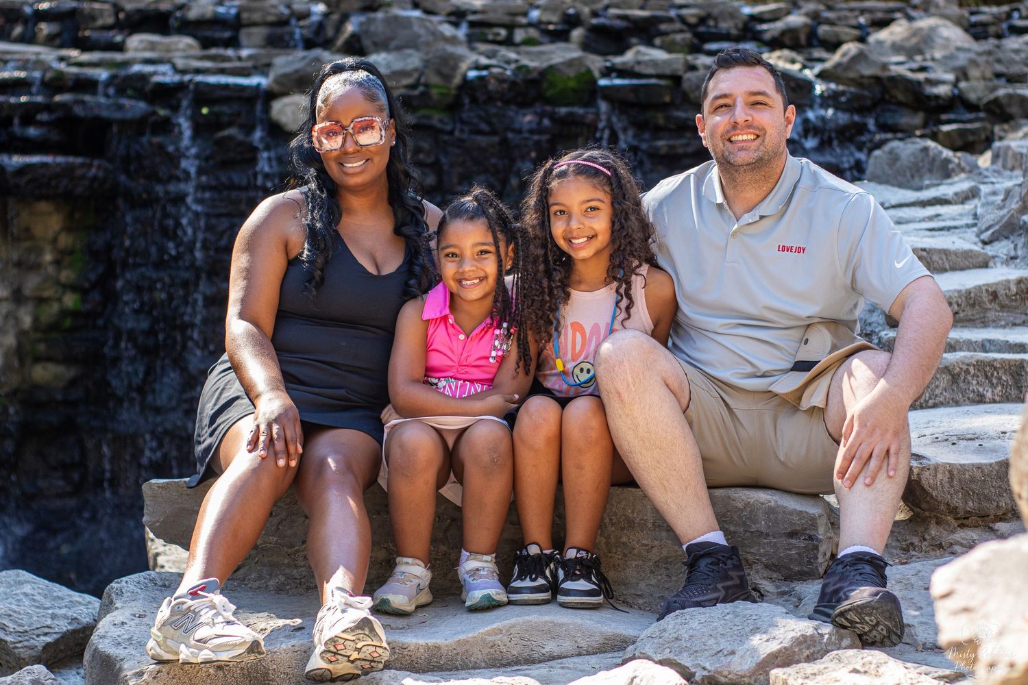 A group of people sitting together on rocky steps outdoors during a sunny day.