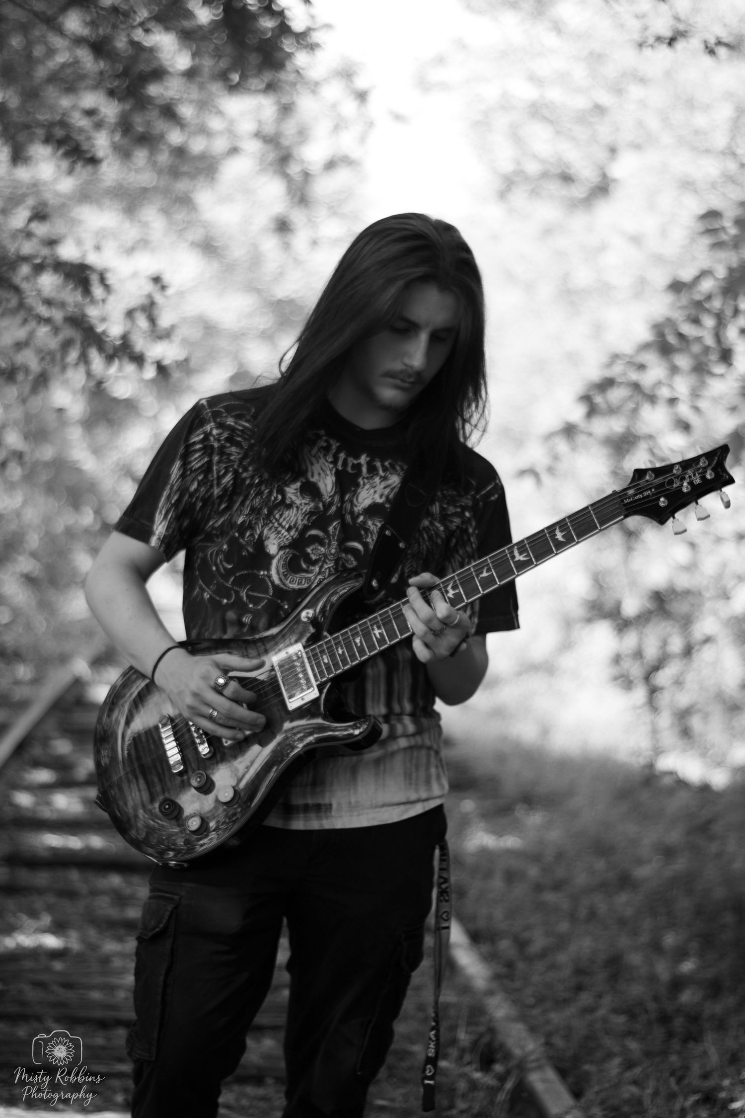Black and white photo series of a musician playing an electric guitar outdoors with a soft bokeh background effect.