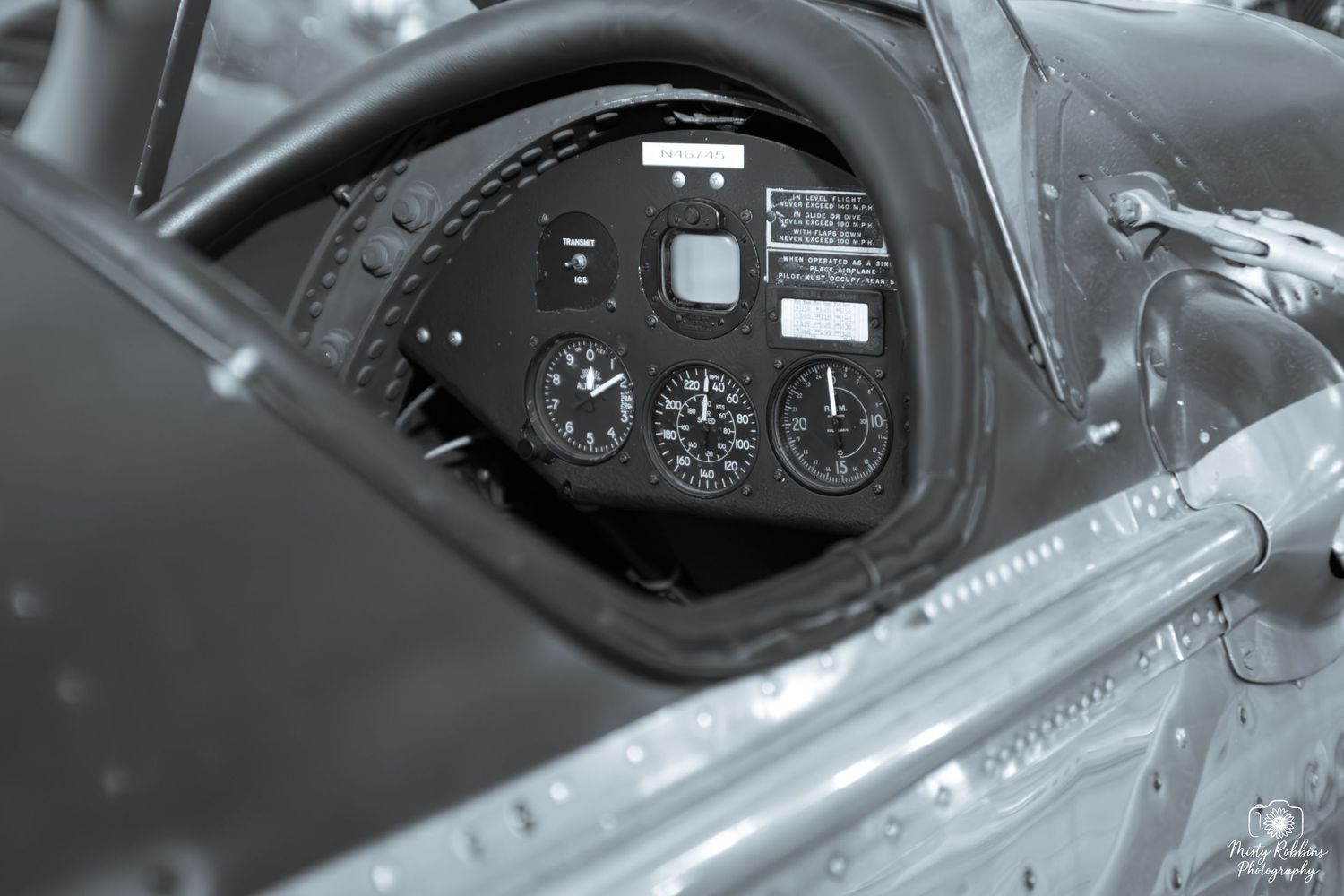 Black and white close-up of a vintage aircraft cockpit instrument panel with gauges and controls.