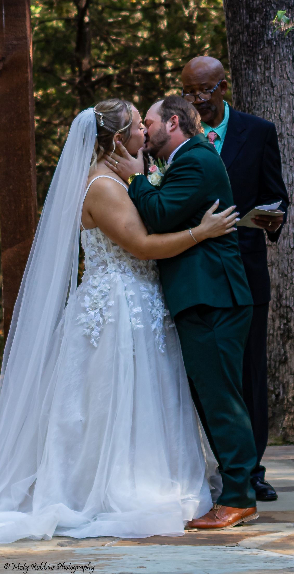 A series of wedding ceremony photos showing a couple's first kiss as newlyweds under a forest canopy.