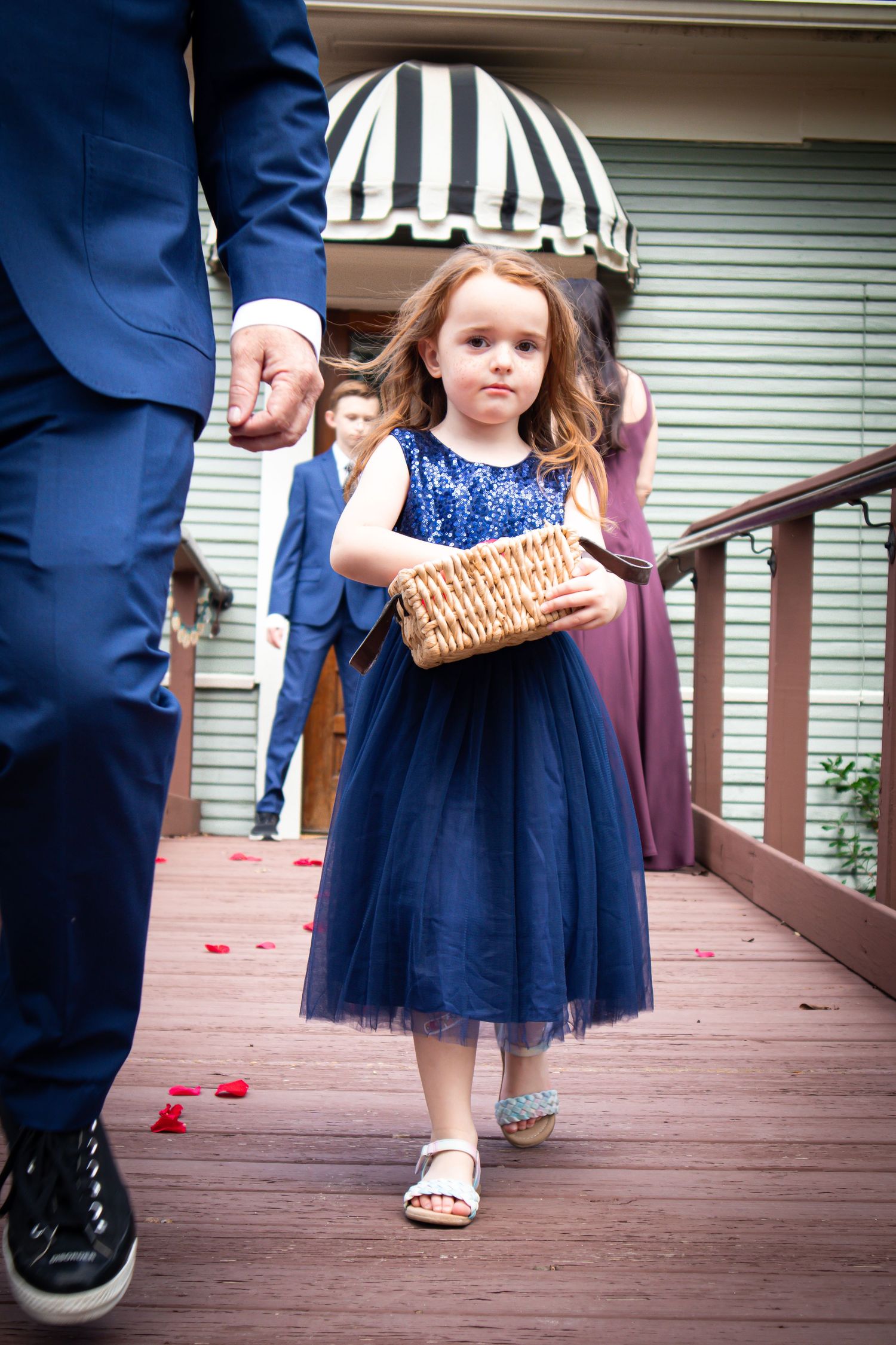 Close-up shots of navy blue formal wear and tulle dress details while walking on a brown wooden deck.