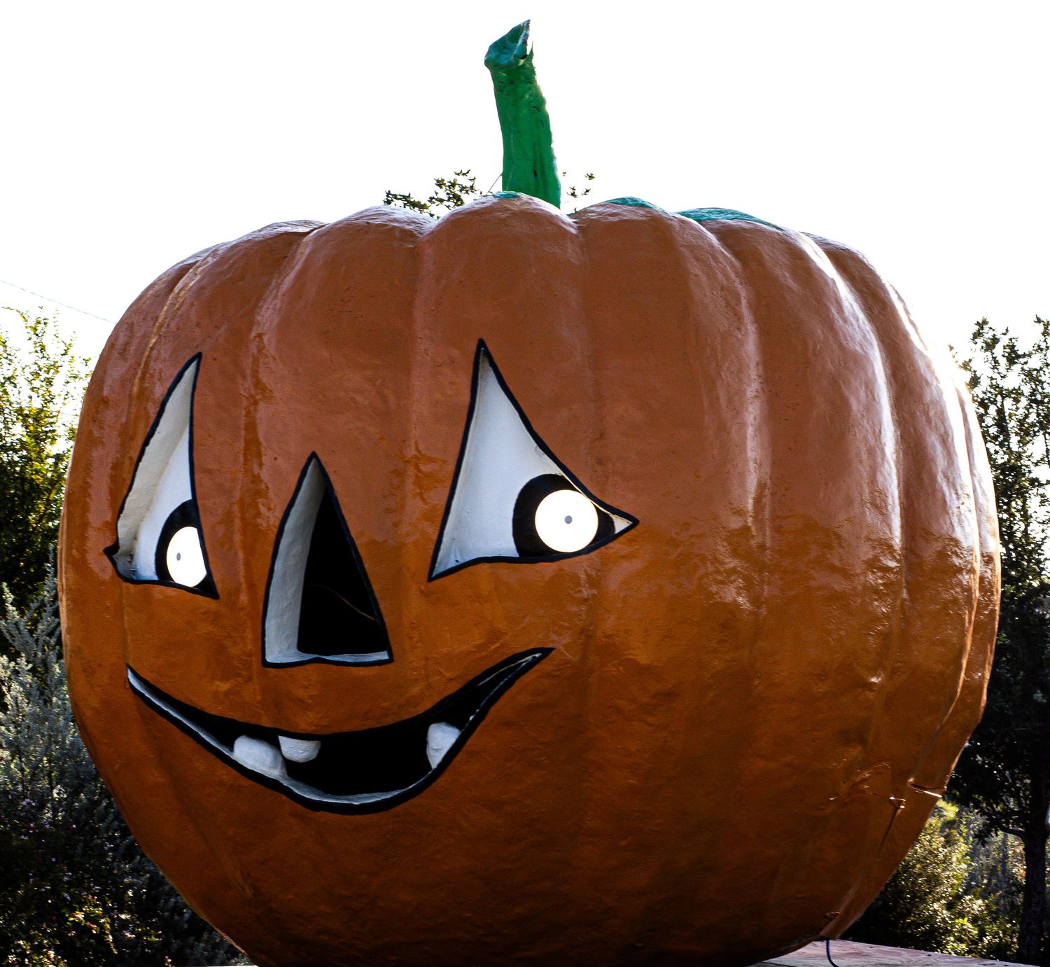 Giant decorative Halloween pumpkins with carved faces displayed outdoors.