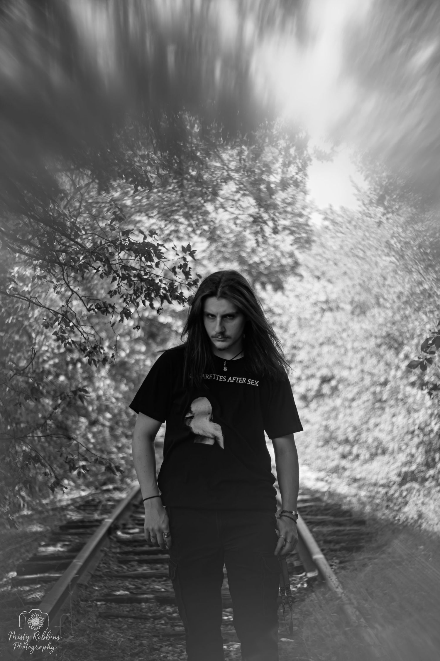 A sequence of black and white photos showing someone in a black t-shirt walking along a tree-lined path with motion blur effects.