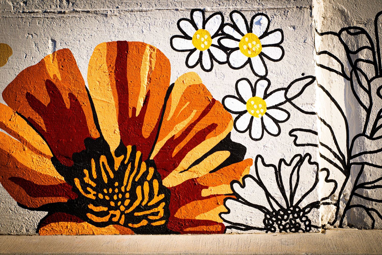 Artistic mural featuring orange flowers and white daisies painted on a textured wall.