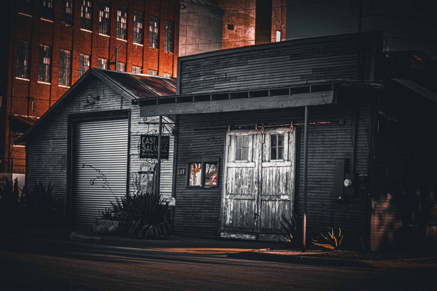 Dark industrial buildings illuminated with warm orange lighting at night.