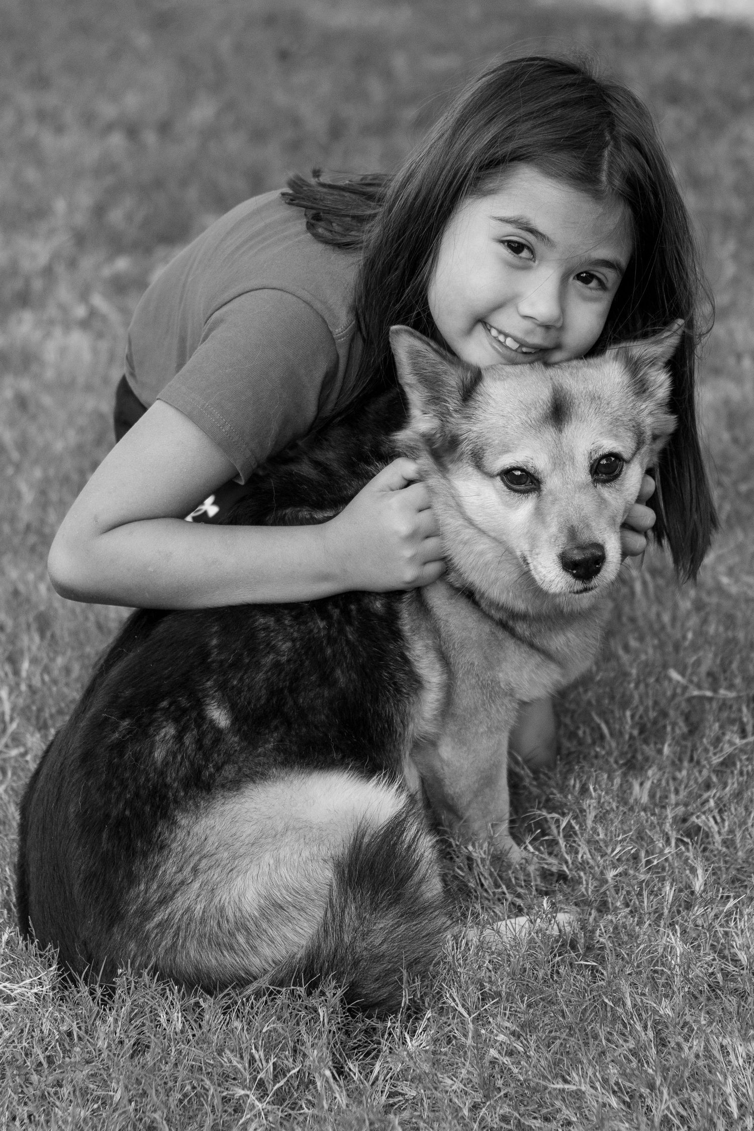 Black and white photo series showing a person hugging and bonding with a small Chihuahua mix dog on grass.