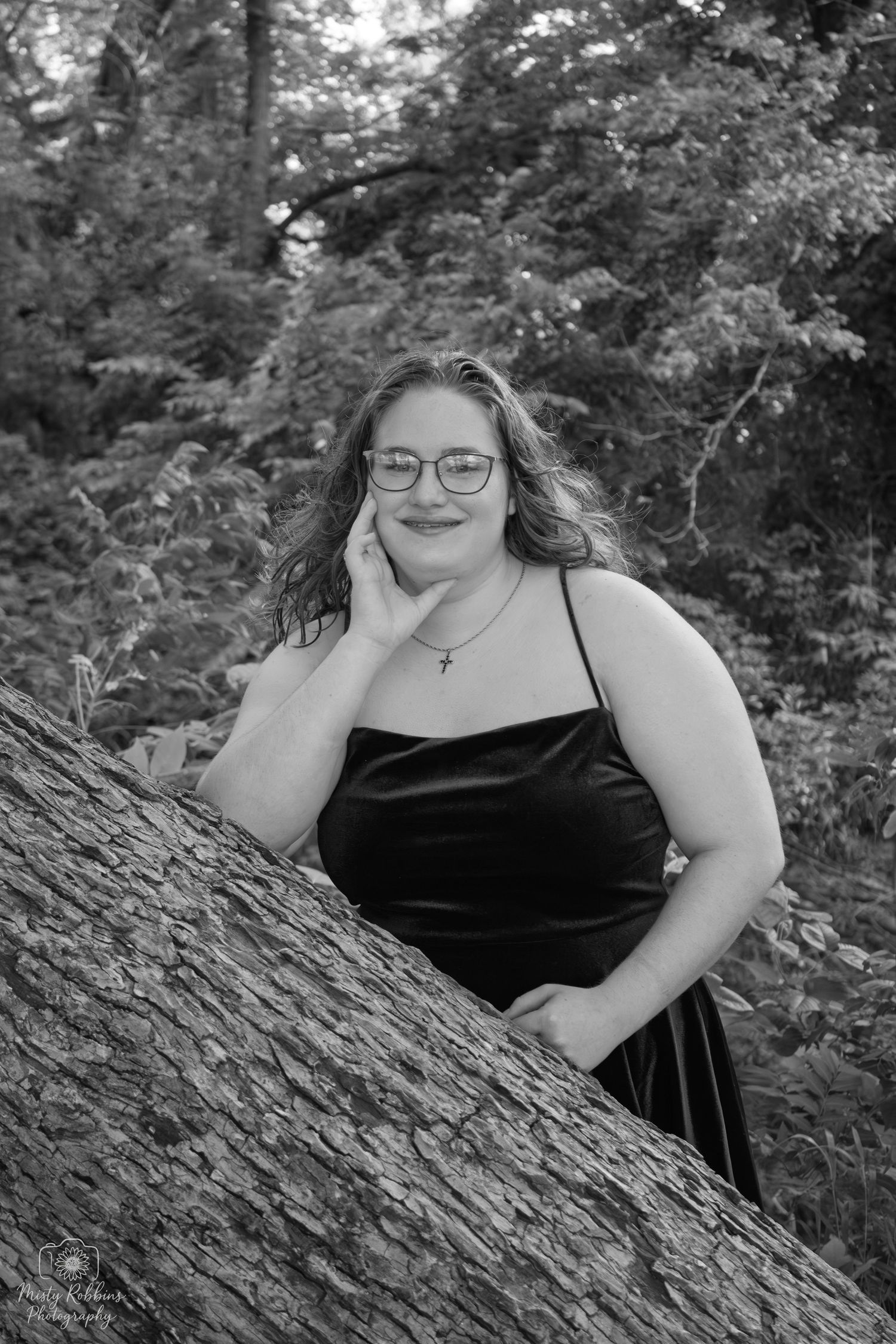 Black and white portrait series of someone in a sleeveless dress reclining against a tree trunk outdoors.