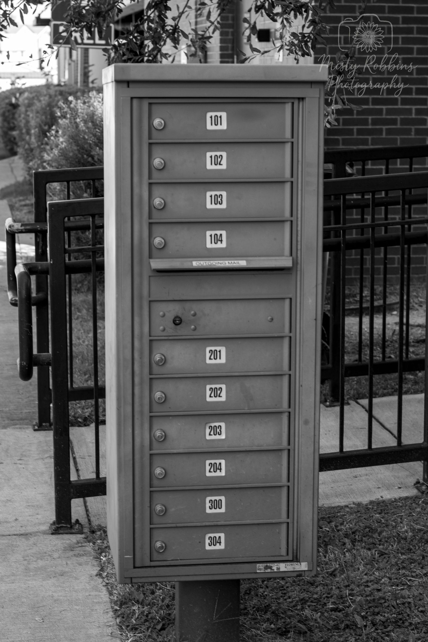 Row of gray metal mailboxes mounted on a brick wall with numbered slots.