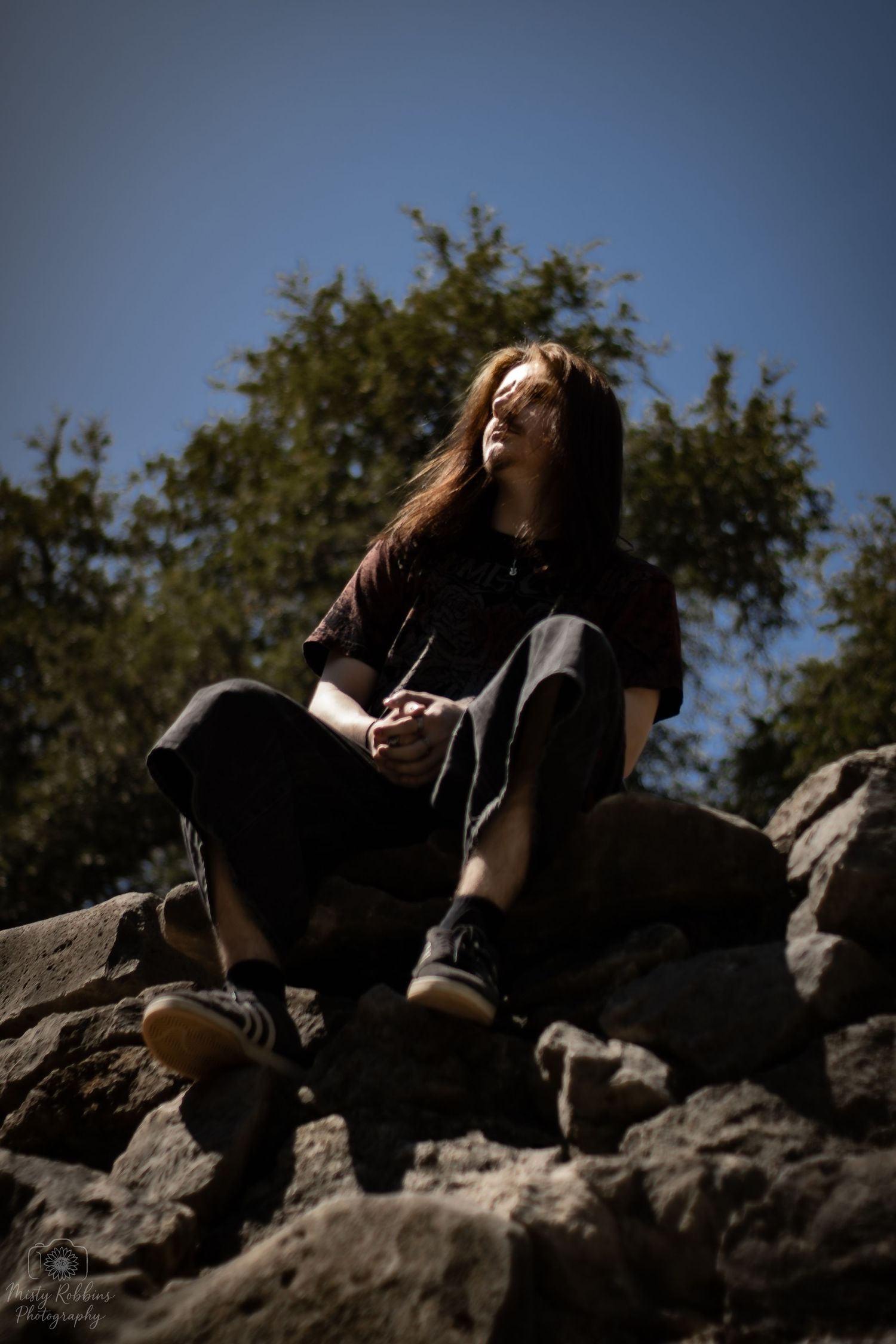 A sequence of silhouetted figures sitting on rocky outcrops against a bright sky in a contemplative series of poses.