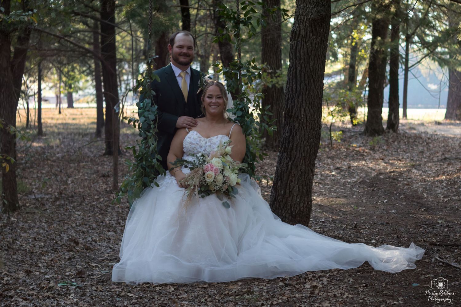 A couple poses in a scenic wooded area during their outdoor wedding ceremony.
