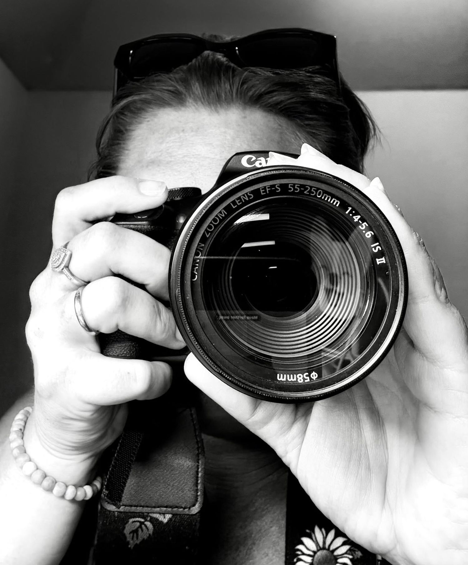 Black and white photo of hands holding a camera with a large zoom lens.