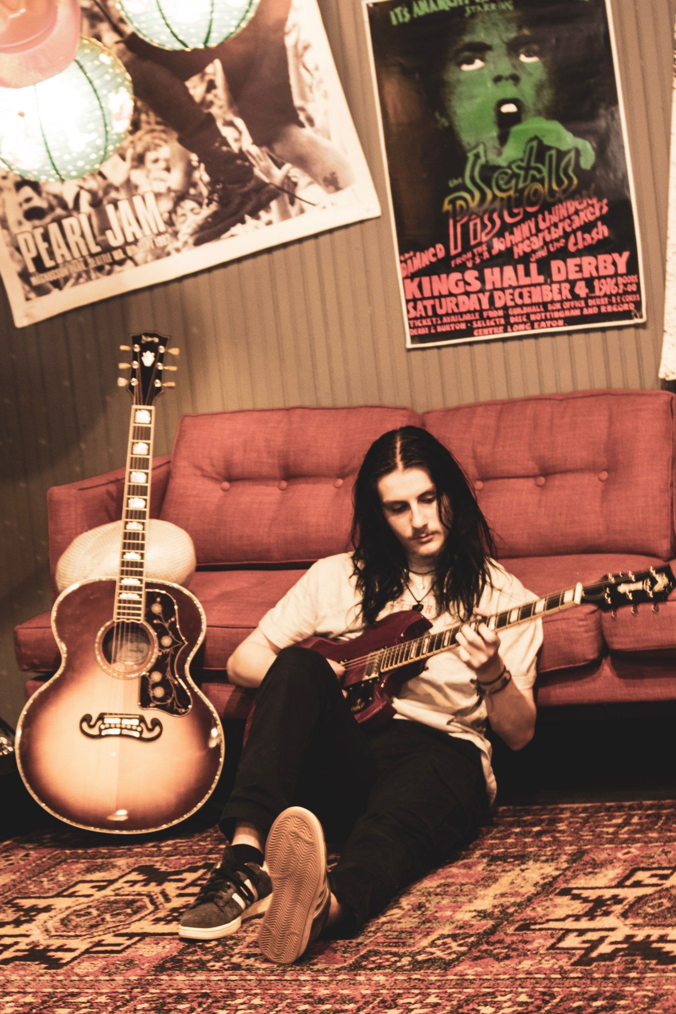 A sepia-toned triptych photo shows a person sitting on a red couch with an acoustic guitar in different poses.