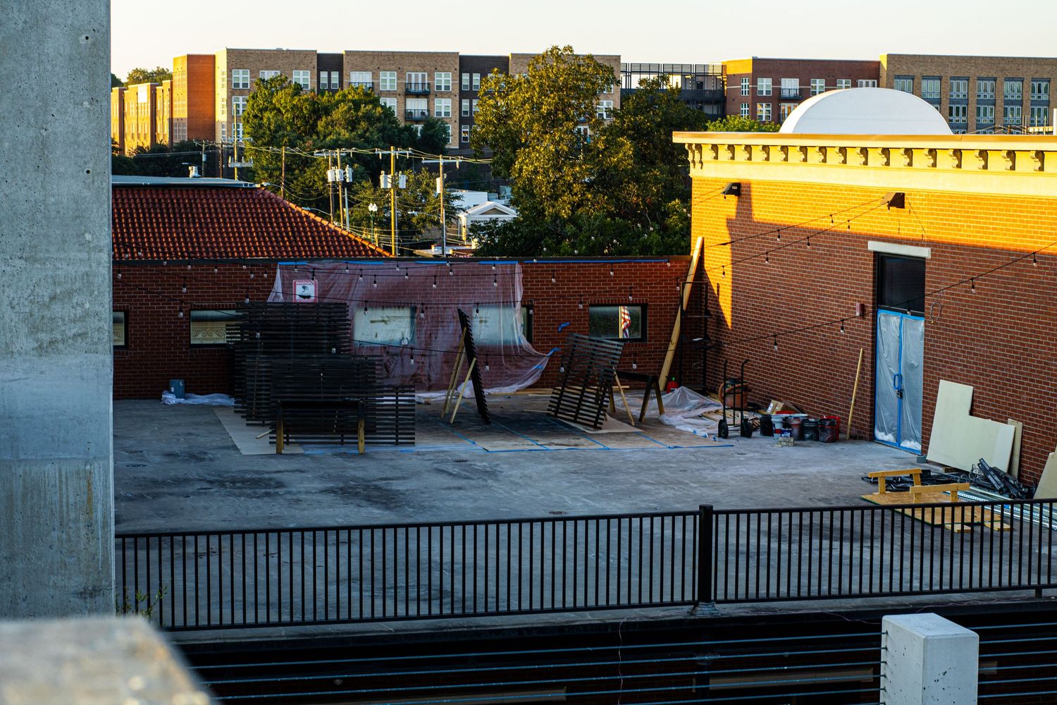 Urban rooftop view showing commercial buildings and railings during sunset.