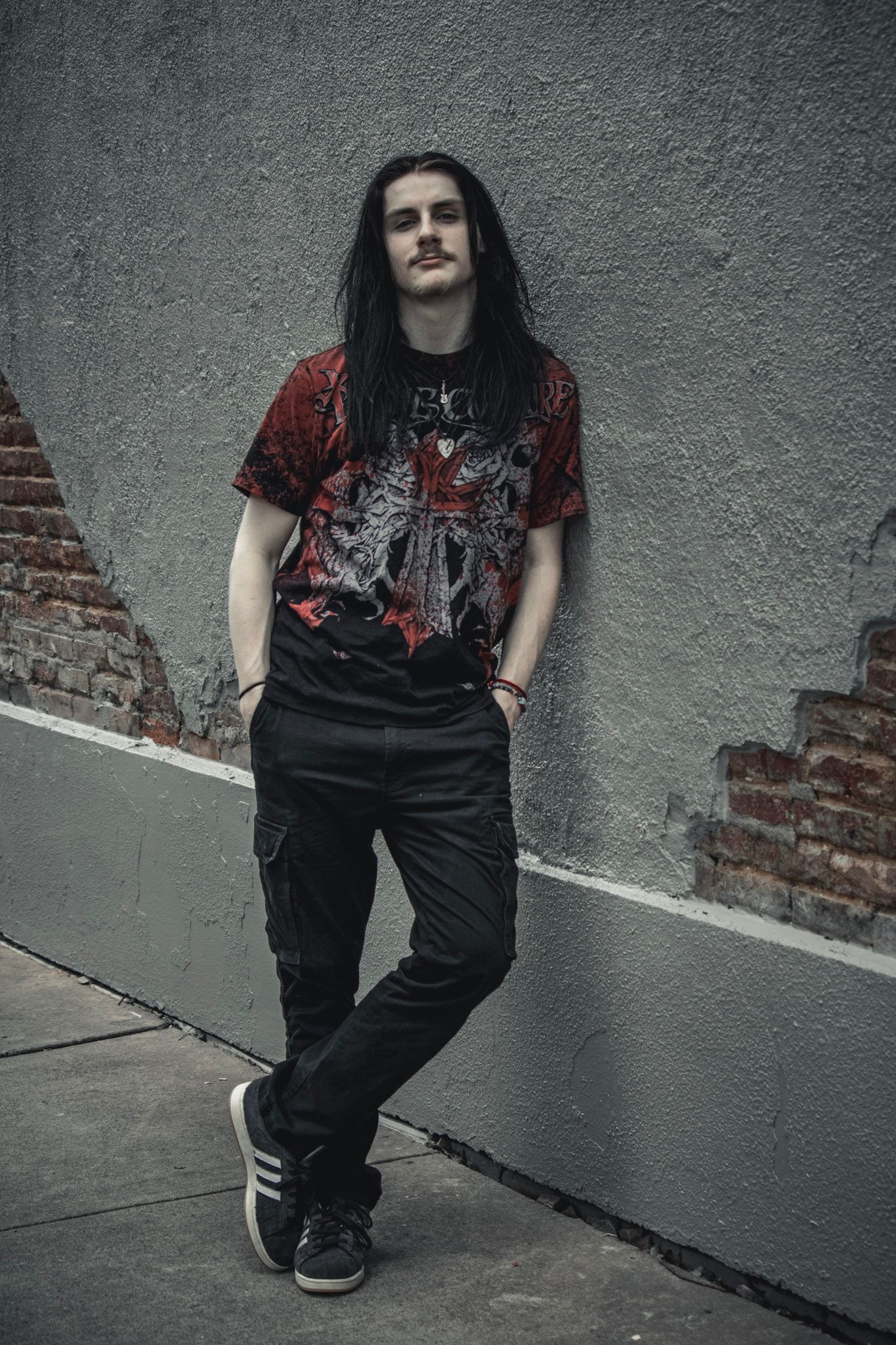 A sequence of five photos showing someone wearing black pants and a dark graphic t-shirt against a gray wall.