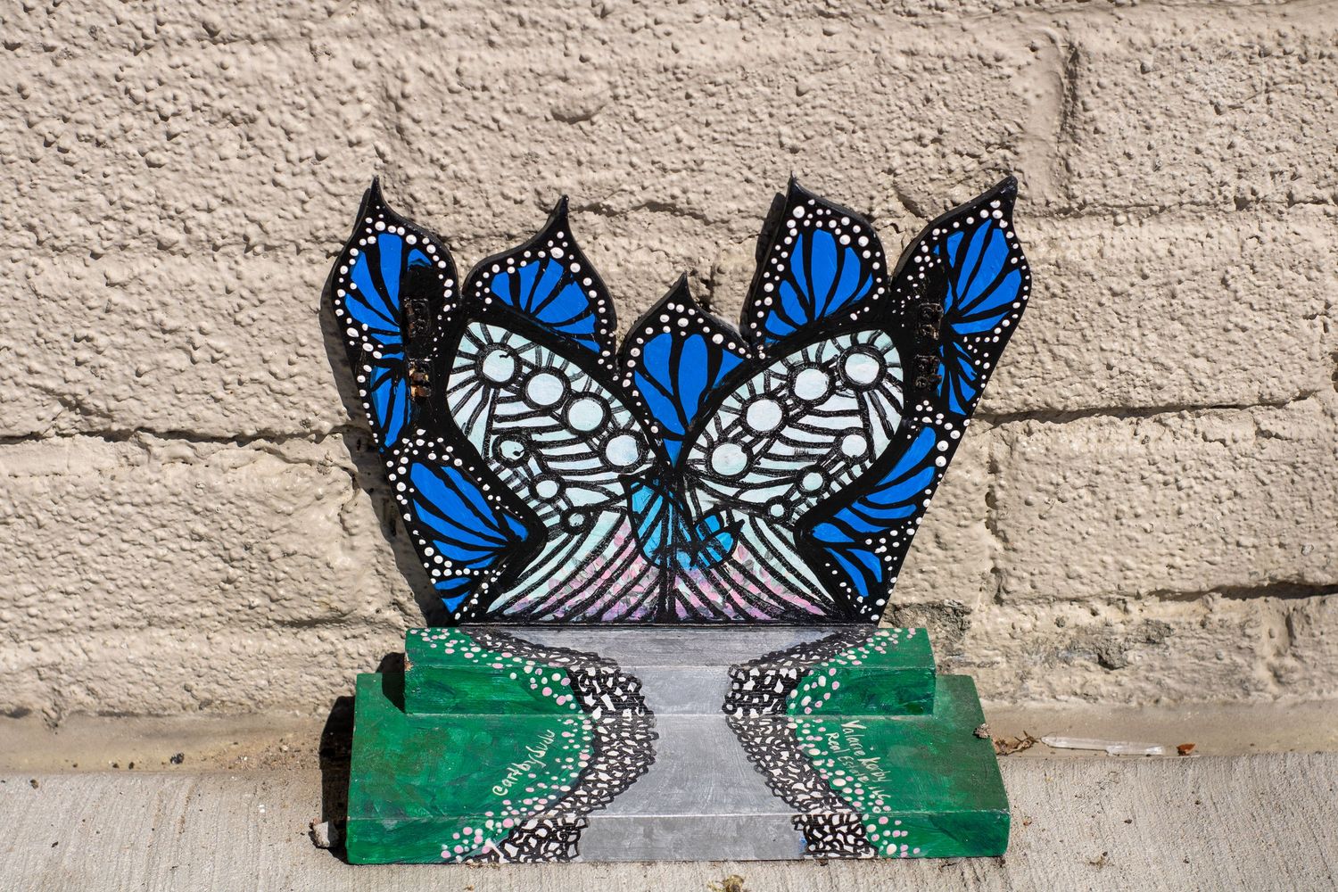 Blue butterfly mural painted on a textured white wall with green accents.