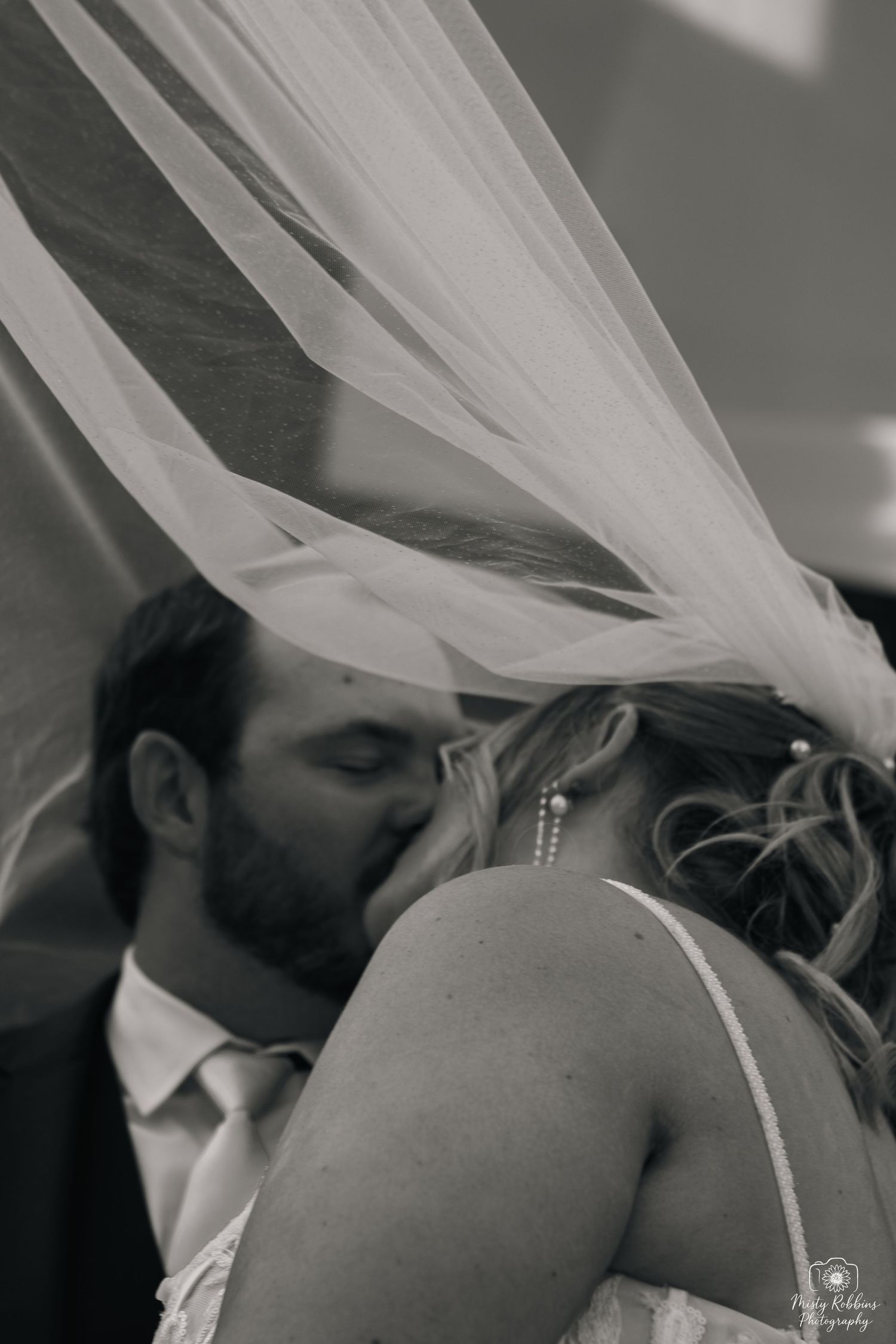 Romantic black and white wedding photography sequence capturing intimate moments between newlyweds under flowing veil.