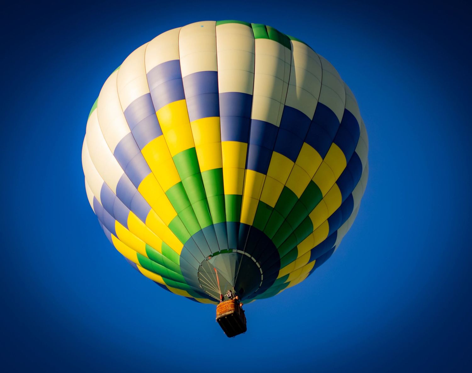 Colorful hot air balloon with yellow, green and white stripes against deep blue sky in multiple views.