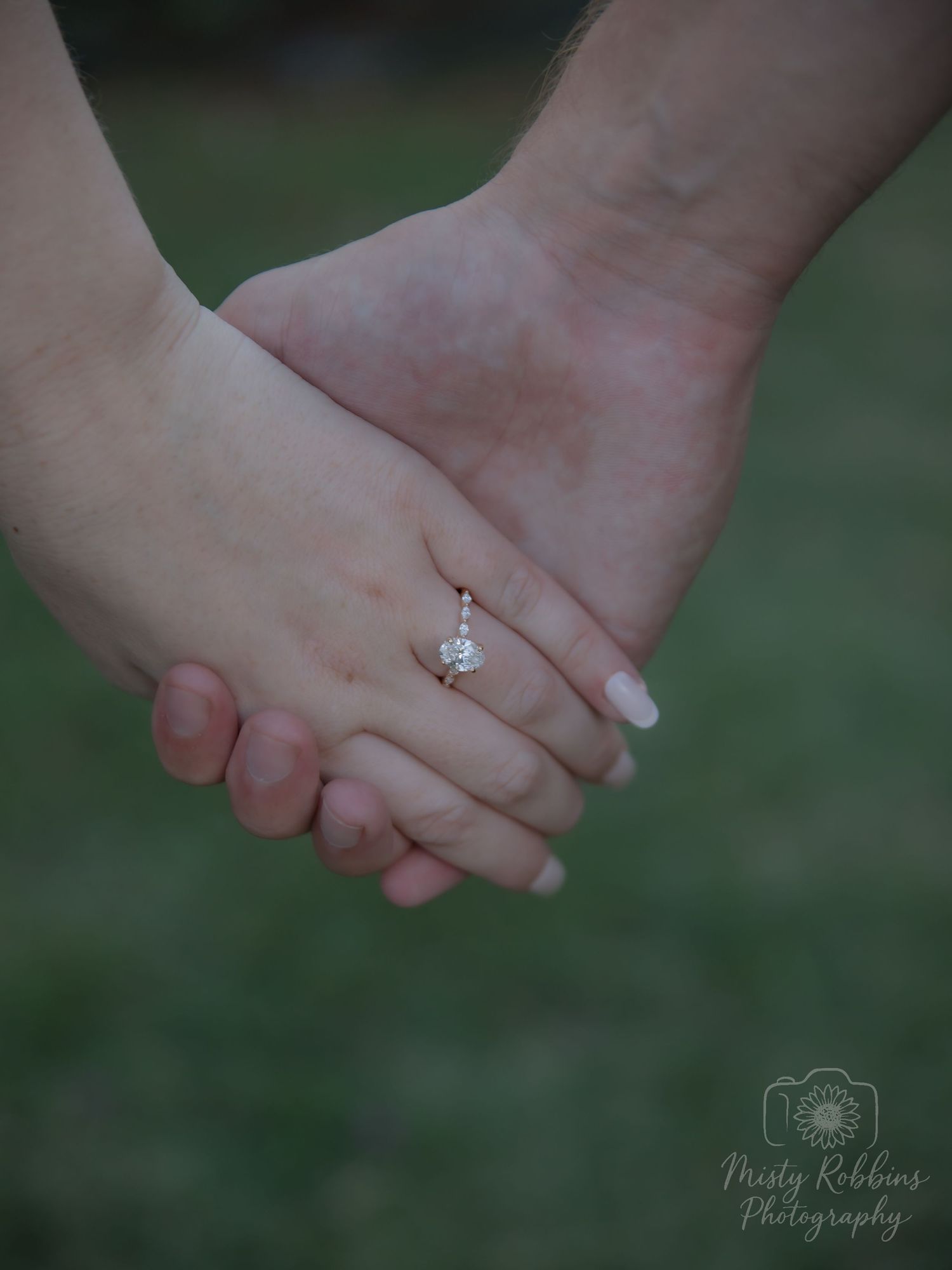 Close-up sequence of hands holding each other and showing engagement ring against blurred green outdoor background.