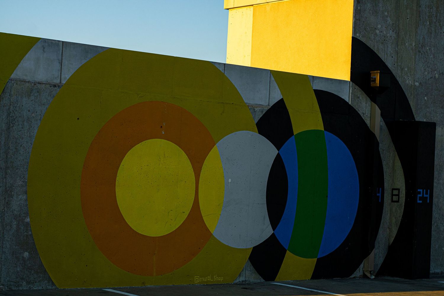 Abstract geometric pattern with yellow, black, and blue circles on a wall.