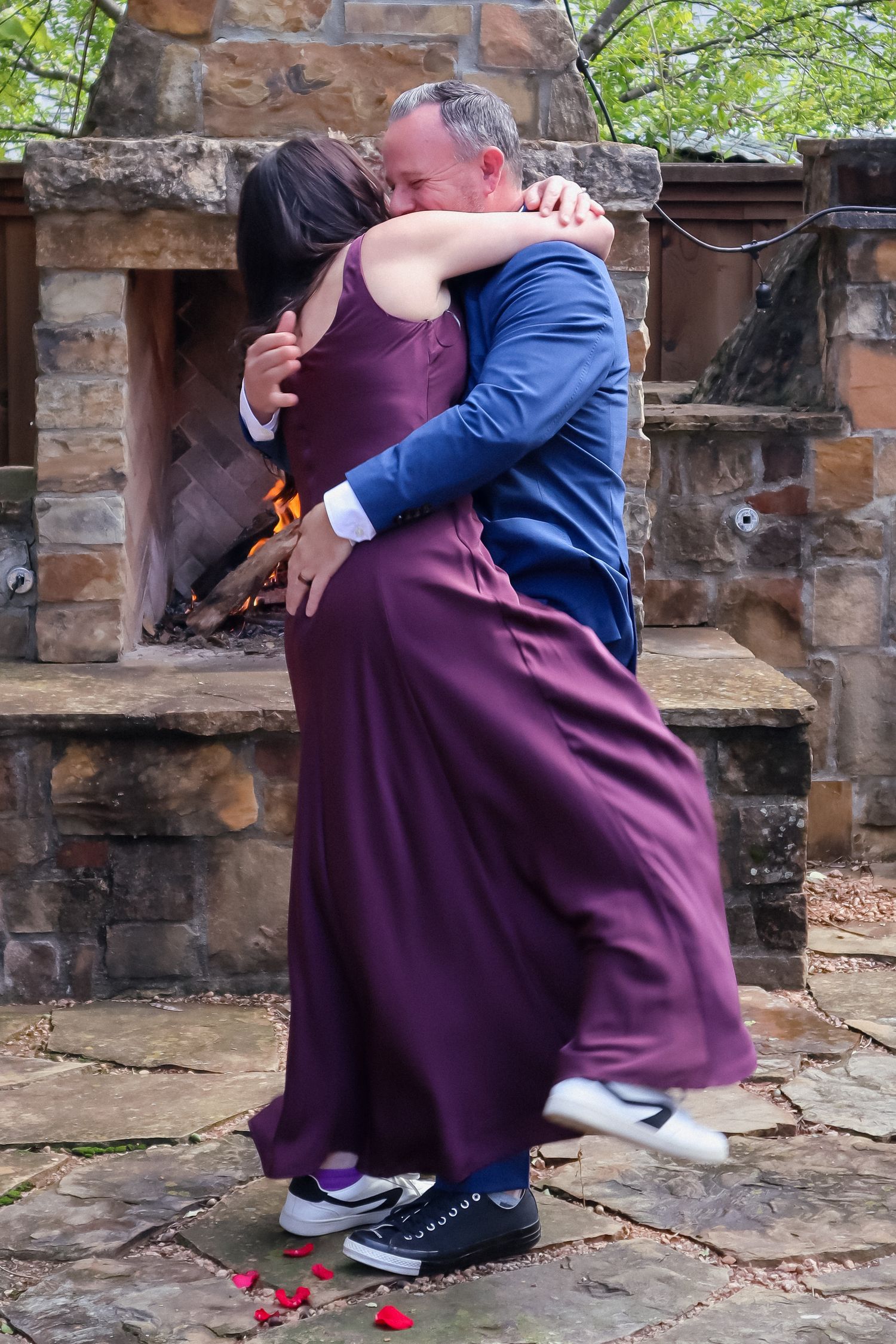 Family members in formal attire embrace while sitting on stone steps outdoors.