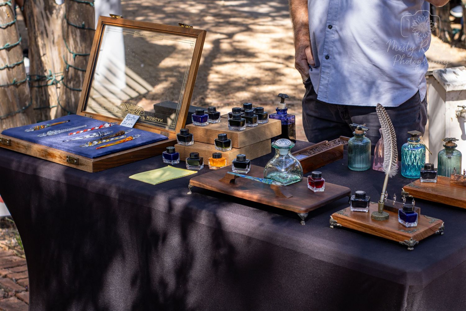 Professional audio equipment and turntables displayed on wooden tables at an outdoor event setup.